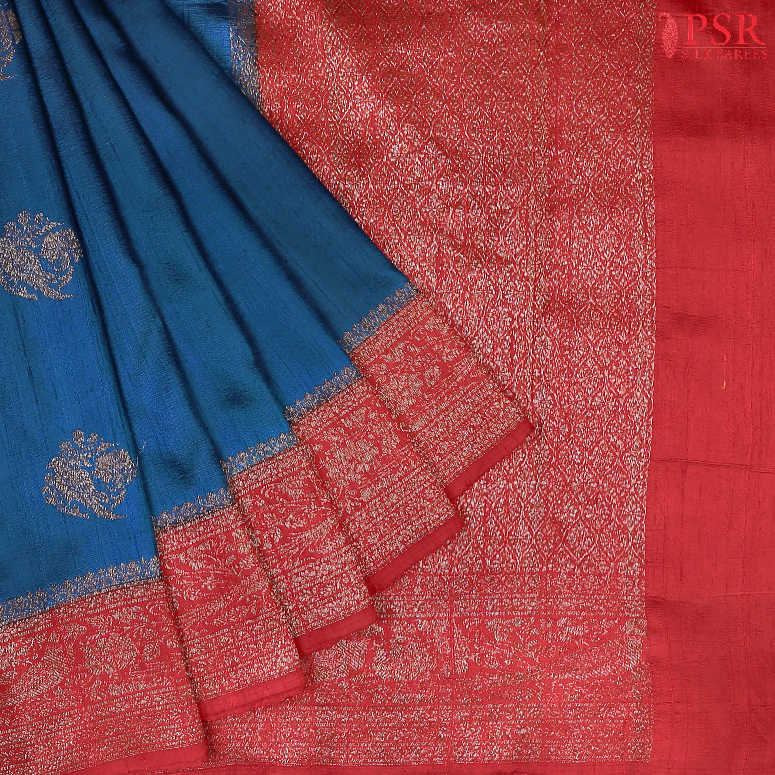 Unveil a world of elegance with this stunning Peacock Blue Banaras Jute Silk Saree, beautifully paired with a vibrant Red accent.