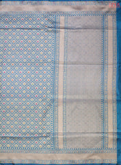 PSR Silks presents a stunning Peacock Blue Banarasi Silk Saree, showcasing a masterfully woven zari lattice pattern, beautifully embellished with vibrant thread work.