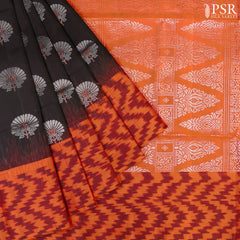 Embrace sophistication with PSR Silks' enchanting Black Soft Silk Saree, perfectly paired with a vibrant Lava Orange combination. This elegant saree is adorned with intricate silver and copper zari floral motifs, radiating timeless beauty.