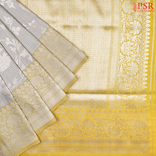 PSR Silks presents a delightful Gainsboro Grey Banarasi Silk Saree, beautifully paired with a refreshing Olive Yellow. 