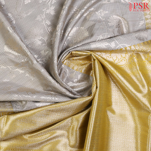 PSR Silks presents a delightful Gainsboro Grey Banarasi Silk Saree, beautifully paired with a refreshing Olive Yellow. 