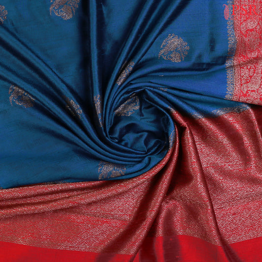 Unveil a world of elegance with this stunning Peacock Blue Banaras Jute Silk Saree, beautifully paired with a vibrant Red accent. 
