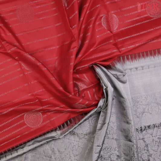 Celebrate elegance with our enchanting Red Soft Silk Saree, beautifully complemented by a sophisticated Grey hue